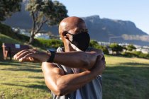 Fit старший африканский американец в маске для лица упражнения на открытом воздухе растяжения. гигиена здорового образа жизни на открытом воздухе во время пандемии коронавируса. — стоковое фото