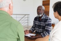 Разнообразная группа пожилых людей разговаривает во время групповой терапии дома. здоровье фитнес-благополучие в доме престарелых. — стоковое фото