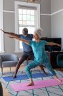 Senioren-Mixed-Race-Paar in Sportkleidung beim Training im Wohnzimmer. Während der Quarantäne zu Hause bleiben und sich selbst isolieren. — Stockfoto