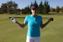 Портрет белой женщины на поле для гольфа, держащей клюшку для гольфа за плечами. спорт досуг хобби гольф здоровый образ жизни на открытом воздухе. — стоковое фото