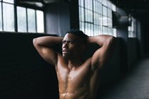 Homem afro-americano de pé e flexionando seus músculos em um edifício urbano vazio. fitness urbano estilo de vida saudável. — Fotografia de Stock