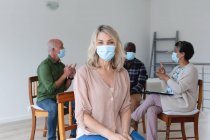 Diverso grupo de personas mayores que usan máscaras faciales hablando durante una sesión de terapia de grupo en casa. salud higiene bienestar en el hogar de ancianos durante la pandemia de coronavirus covid 19. - foto de stock
