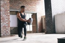 Homem afro-americano a exercitar-se com uma bola de remédios num edifício urbano vazio. fitness urbano estilo de vida saudável. — Fotografia de Stock