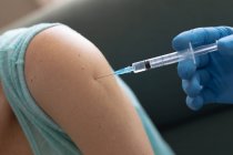 Ärztin mit OP-Handschuhen gibt Seniorin zu Hause 19 Impfungen. Gesundheitsfürsorge und Hygiene zu Hause in Selbstisolation während der Quarantäne. — Stockfoto