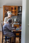 Senioren-Mischlingspaar mit Laptop beim gemeinsamen Bezahlen von Rechnungen im Speisesaal. Während der Quarantäne zu Hause bleiben und sich selbst isolieren. — Stockfoto