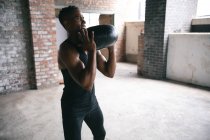 Homem afro-americano a exercitar-se com uma bola de remédios num edifício urbano vazio. fitness urbano estilo de vida saudável. — Fotografia de Stock