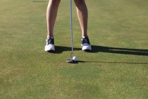 Low section of woman putting ball with club on golf course. sport leisure hobbies golf healthy outdoor lifestyle. — Stock Photo