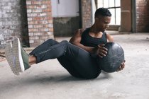 Afrikanischer Mann beim Training mit einem Medizinball in einem leeren städtischen Gebäude. urbane Fitness gesunder Lebensstil. — Stockfoto