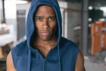 Retrato de um homem afro-americano com capuz a olhar para a câmara num edifício urbano vazio. fitness urbano estilo de vida saudável. — Fotografia de Stock