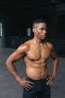 Afrikanischer Mann steht und lässt seine Muskeln in einem leeren städtischen Gebäude spielen. urbane Fitness gesunder Lebensstil. — Stockfoto