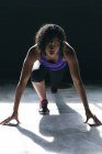 Африканская американка в спортивной одежде, стоящая на коленях в пустом городском здании. здоровый образ жизни. — стоковое фото
