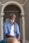 Retrato de um americano africano sénior a olhar para a câmara e a sorrir. ficar em casa em auto-isolamento durante o confinamento de quarentena. — Fotografia de Stock