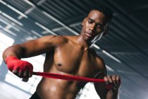 African american boxer taping hands for training in an empty urban building. urban fitness healthy lifestyle. — Stock Photo