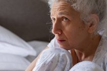 Mujer caucásica mayor sintiéndose débil sentada en la cama. permanecer en casa en aislamiento durante el bloqueo de cuarentena. - foto de stock