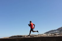 Adatto all'uomo anziano afroamericano che si allena correndo su un sentiero costiero roccioso. sano stile di vita fitness all'aperto pensionamento. — Foto stock