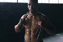 Ritratto di uomo afroamericano che salta la corda sulle spalle in un edificio urbano vuoto. fitness urbano stile di vita sano. — Foto stock