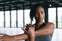 Portrait of african american woman standing in empty urban building looking at camera and stretching. urban fitness healthy lifestyle. — Stock Photo