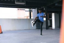 Африканский американец делает трюки с мячом в пустом городском здании. здоровый образ жизни. — стоковое фото