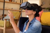 Caucasian woman wearing vr headset sitting on floor at home. Staying at home in self isolation during quarantine lockdown. — Stock Photo