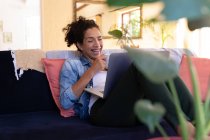 Mulher branca sorrindo usando laptop em chamada de vídeo sentado no sofá em casa. Ficar em casa em auto-isolamento durante o bloqueio de quarentena. — Fotografia de Stock