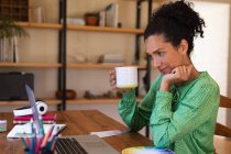 Mulher branca usando laptop em videochamada, segurando caneca, trabalhando em casa. Ficar em casa em auto-isolamento durante o bloqueio de quarentena. — Fotografia de Stock