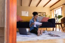 Caucasian woman sitting on floor holding documents, working from home. Staying at home in self isolation during quarantine lockdown. — Stock Photo