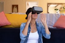 Femme caucasienne portant casque vr assis sur le sol à la maison. Rester à la maison en isolement personnel pendant le confinement en quarantaine. — Photo de stock