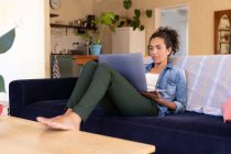 Mulher branca usando laptop sentado no sofá em casa. ficar em casa em auto-isolamento durante o confinamento de quarentena. — Fotografia de Stock