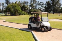 Uomo anziano caucasico e donna che guidano golf buggy sul campo da golf parlando e sorridendo. Golf sport hobby, sano stile di vita pensionamento. — Foto stock