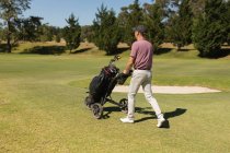 Hombre mayor caucásico caminando a través del campo de golf sosteniendo bolsa de golf. Golf deportes hobby, estilo de vida de jubilación saludable - foto de stock