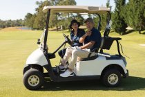 Kaukasische Seniorinnen und Senioren, die auf dem Golfplatz einen Golfbuggy fahren, lächeln. Golf-Sport-Hobby, gesunder Lebensstil im Ruhestand. — Stockfoto