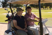 Кавказький старший чоловік і жінка їздять на поле для гольфу, розмовляючи і посміхаючись. Гольф спорт хобі, здоровий спосіб життя на пенсії. — стокове фото