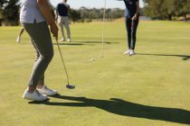 Drei kaukasische ältere Männer und Frauen beobachten den Mann bei der Aufnahme auf dem Grün. Golf-Sport-Hobby, gesunder Lebensstil im Ruhestand — Stockfoto