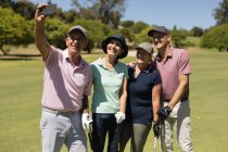 Vier kaukasische Senioren halten Golfschläger in der Hand und machen ein Selfie. Golf-Sport-Hobby, gesunder Lebensstil im Ruhestand — Stockfoto
