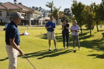 Three caucasian senior man and women watching man preparing for a shot on the green. Golf sports hobby, healthy retirement lifestyle — Stock Photo