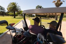 Caucasiano homem sênior e mulher dirigindo buggy de golfe no campo de golfe falando e sorrindo. Esportes de golfe passatempo, estilo de vida de aposentadoria saudável. — Fotografia de Stock