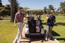 Кавказький старший чоловік і жінка, які беруть ключки для гольфу з мішків для гольфу в багатті. Хобі для гольфу, здоровий спосіб життя на пенсії. — стокове фото