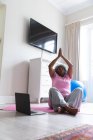 Mujer mayor afroamericana practicando yoga en casa. permaneciendo en casa en aislamiento en cuarentena - foto de stock