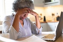 Femme âgée afro-américaine stressée utilisant un ordinateur portable et calculant les finances à la maison. rester à la maison en isolement personnel en quarantaine — Photo de stock