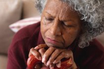 Gros plan d'une femme âgée afro-américaine réfléchie dormant tout en tenant un bâton de marche à la maison. rester à la maison en isolement personnel en quarantaine — Photo de stock