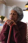 Gros plan d'une femme âgée afro-américaine réfléchie tenant un bâton de marche à la maison. rester à la maison en isolement personnel en quarantaine — Photo de stock