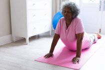Eine afroamerikanische Seniorin praktiziert Yoga und meditiert zu Hause. Zu Hause bleiben in Selbstisolierung in Quarantäne — Stockfoto