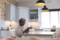 Pensativo afroamericano anciano mujer sosteniendo contenedores de medicamentos vacíos en casa. permaneciendo en casa en aislamiento en cuarentena - foto de stock