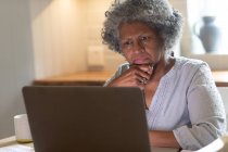 Nachdenkliche afrikanisch-amerikanische Seniorin mit Laptop zu Hause. Zu Hause bleiben in Selbstisolierung in Quarantäne — Stockfoto