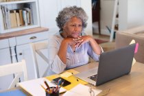 Mulher idosa afro-americana atenciosa fazendo uma videochamada no laptop em casa. ficar em casa em auto-isolamento em quarentena — Fotografia de Stock