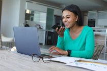 Africano americano mulher falando no smartphone e usando laptop enquanto trabalhava em casa. ficar em casa em auto-isolamento em quarentena — Fotografia de Stock