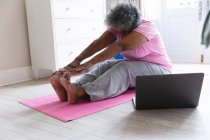 Mujer mayor afroamericana practicando yoga en casa. permaneciendo en casa en aislamiento en cuarentena - foto de stock