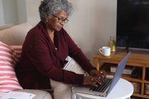 Nachdenkliche afrikanisch-amerikanische Seniorin mit Laptop zu Hause. Zu Hause bleiben in Selbstisolierung in Quarantäne — Stockfoto