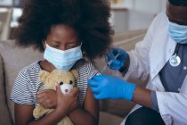 Médico afro-americano a vacinar a criança doente. ficar em casa em auto-isolamento durante o confinamento de quarentena. — Fotografia de Stock