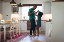 Африканская американка и её отец обнимаются на кухне. оставаться дома в изоляции во время карантинной изоляции. — стоковое фото